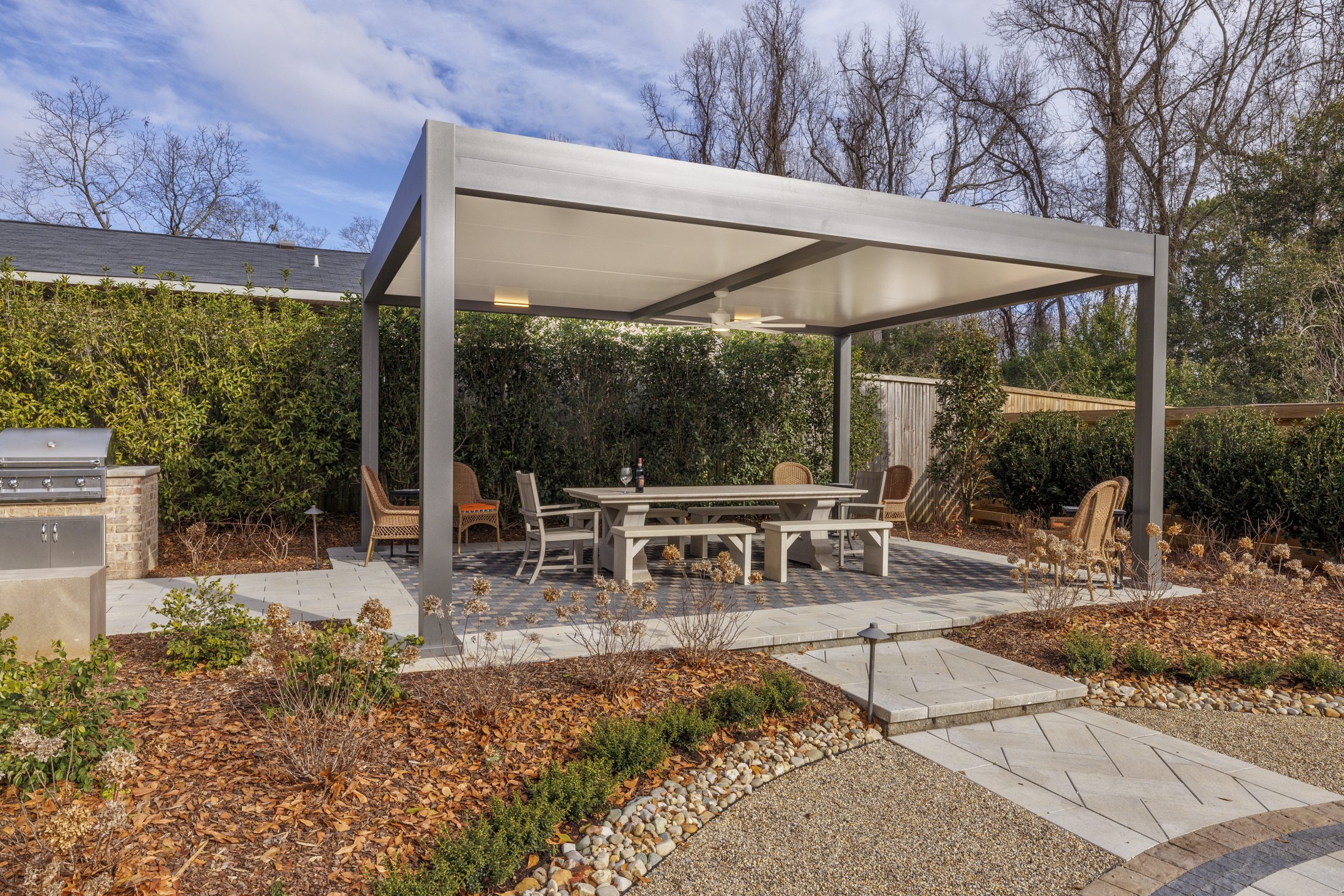 Premium pergola with white panels, ceiling fan, and outdoor kitchen integration