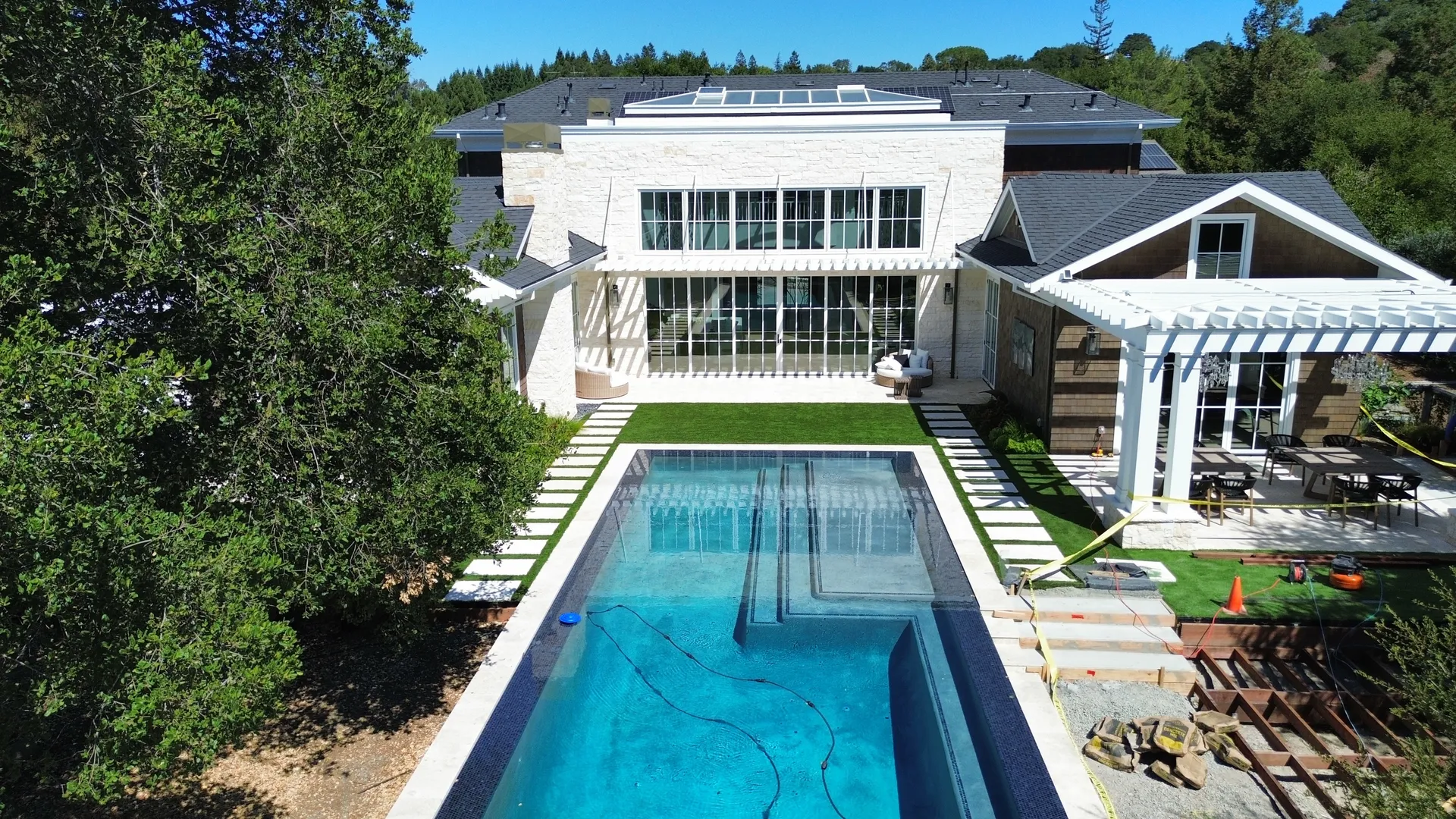 Aerial view of custom lap pool installation with white pergola and surrounding landscape