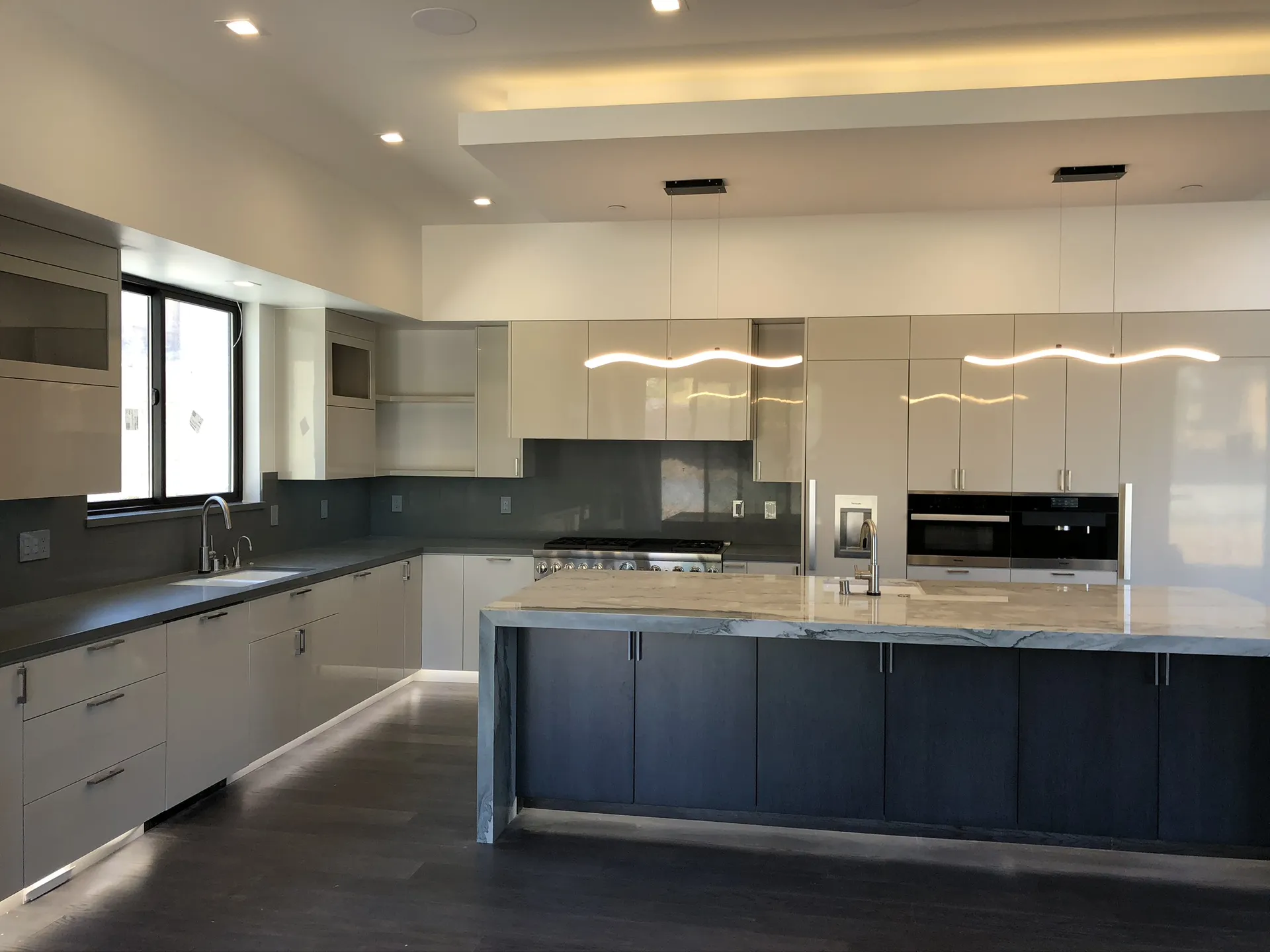 Kitchen with marble countertops, black lower cabinets, and stainless appliances