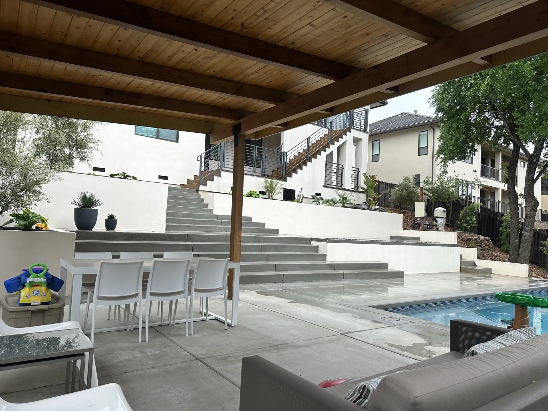 Custom pergola with wood ceiling and cushioned seating overlooking pool